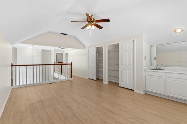 unfurnished room featuring visible vents, a sink, light wood-style floors, lofted ceiling, and ceiling fan