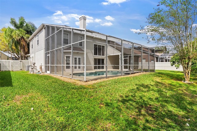 rear view of property featuring a lawn, a chimney, and a fenced backyard