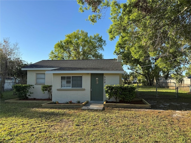 view of front of house with stucco siding, a front lawn, and fence