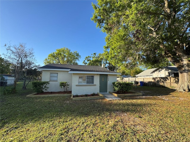 view of front of house featuring stucco siding, a front lawn, and fence