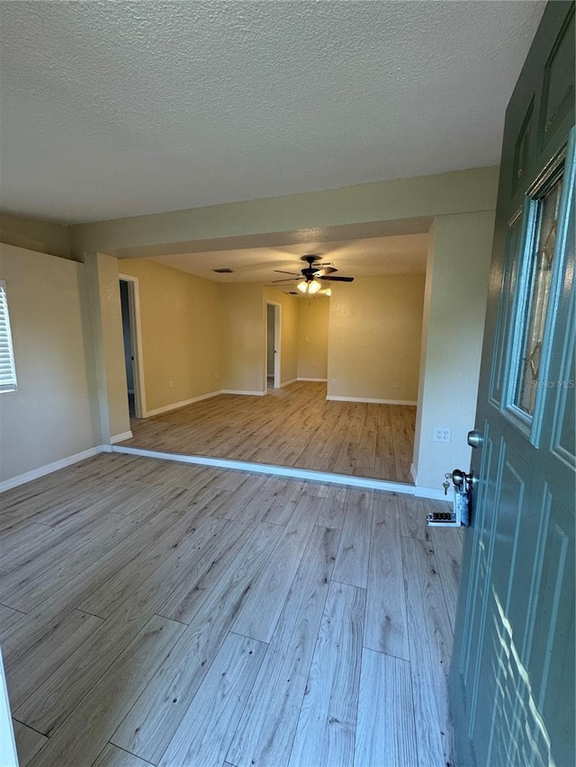 spare room featuring a textured ceiling, a ceiling fan, baseboards, and wood finished floors