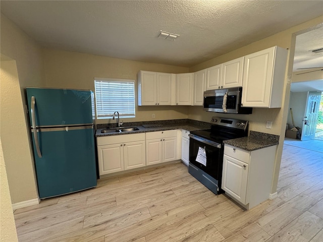 kitchen featuring visible vents, freestanding refrigerator, a sink, range with electric cooktop, and stainless steel microwave