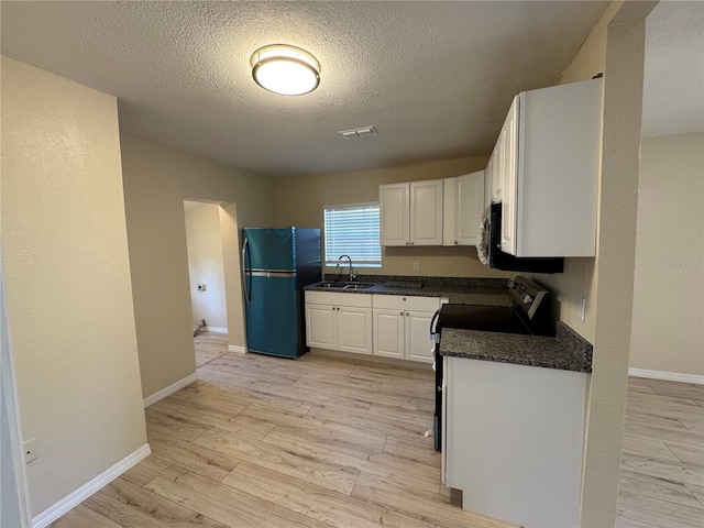 kitchen featuring dark countertops, visible vents, light wood-style flooring, appliances with stainless steel finishes, and a sink