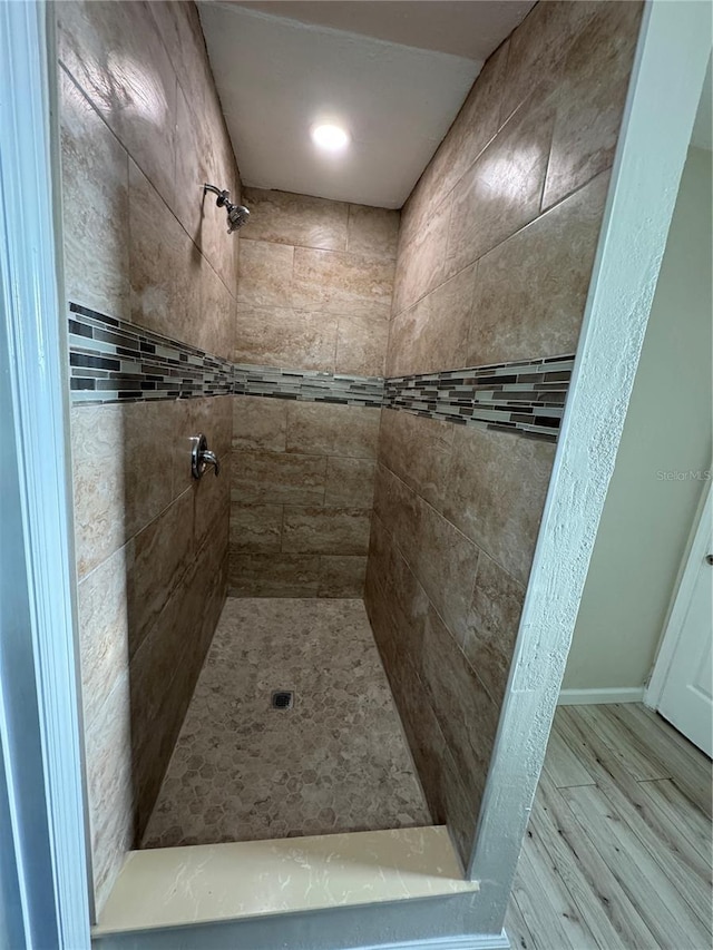 full bathroom featuring a tile shower and wood finished floors