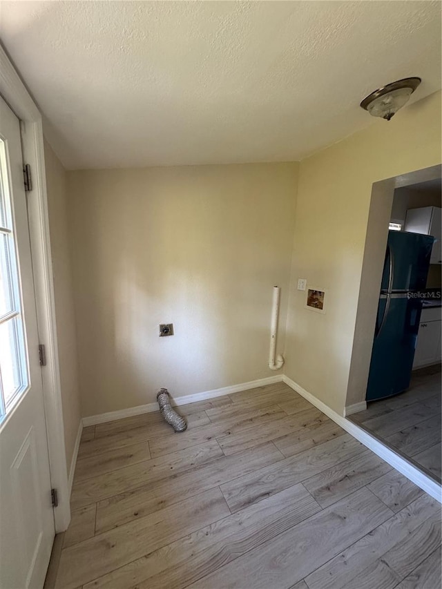 laundry room with baseboards, laundry area, a textured ceiling, and light wood-style floors