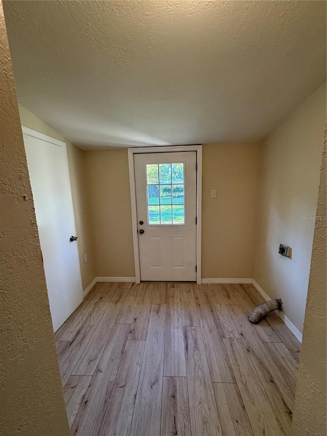 entryway with light wood-style floors, baseboards, and a textured ceiling