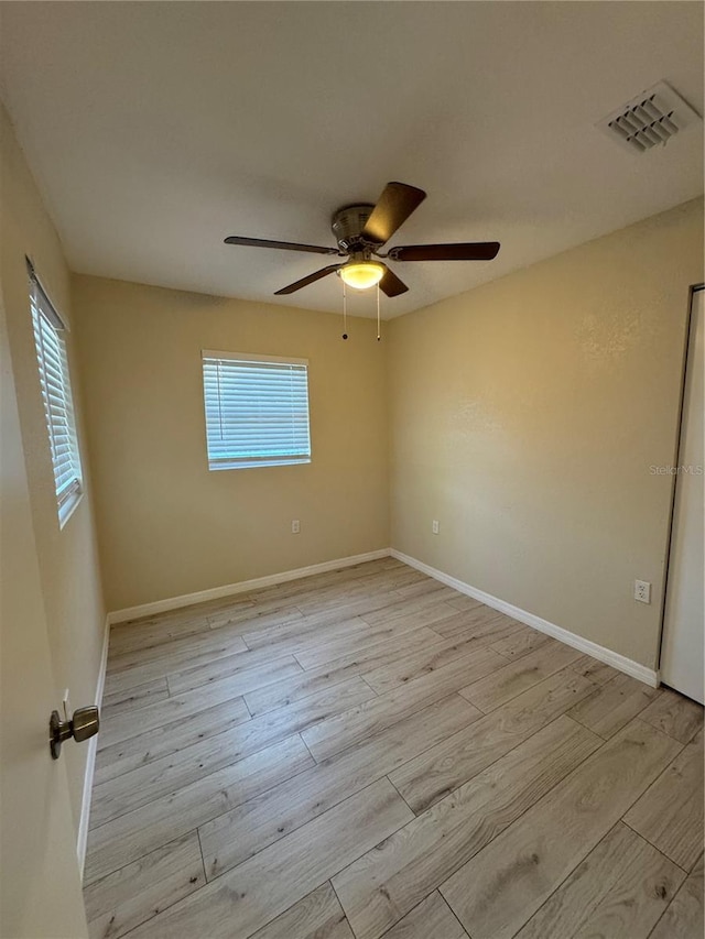 empty room with visible vents, light wood-style flooring, plenty of natural light, and baseboards