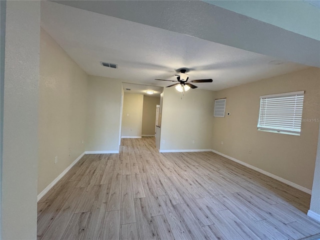 spare room featuring a ceiling fan, visible vents, baseboards, a textured ceiling, and light wood-type flooring