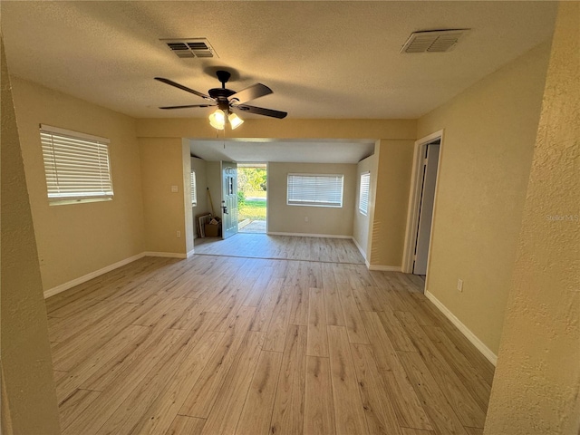 unfurnished room featuring light wood-type flooring, visible vents, baseboards, and a textured ceiling