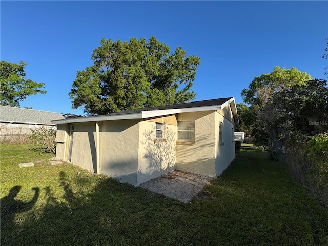 view of home's exterior featuring a yard, fence, and stucco siding