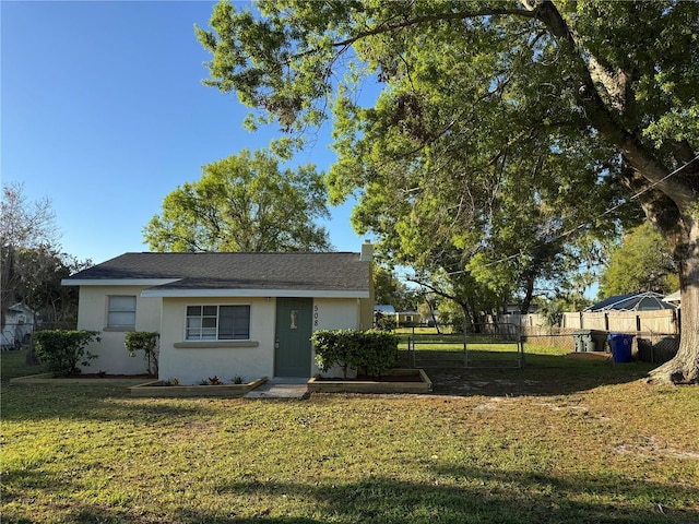 view of front of house featuring stucco siding, a front yard, and fence