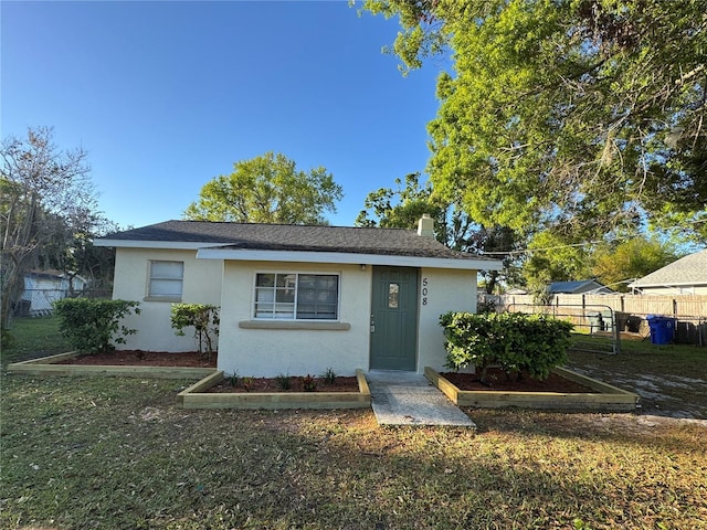 bungalow-style house with a front lawn, fence, and stucco siding