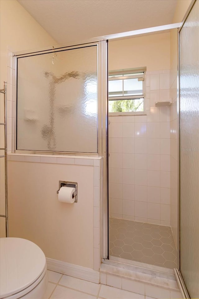 bathroom with tile patterned flooring, toilet, and a shower stall