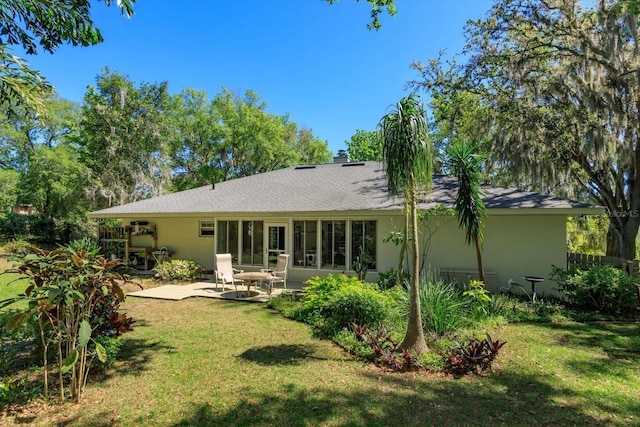 back of house with a patio, a lawn, and stucco siding