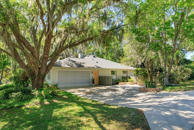 ranch-style house featuring concrete driveway, an attached garage, and fence