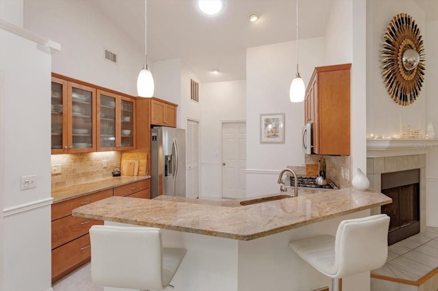 kitchen featuring a sink, brown cabinetry, stainless steel appliances, a peninsula, and visible vents