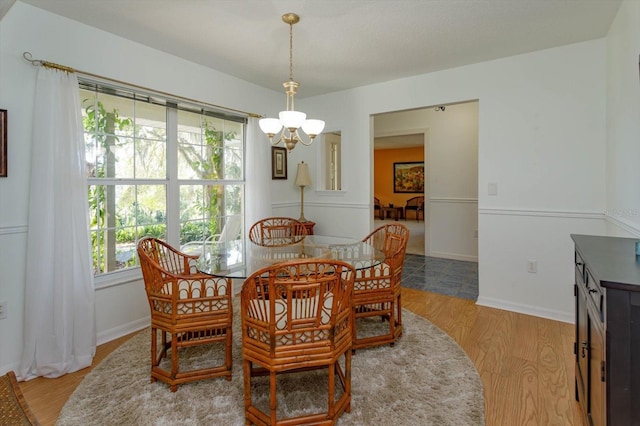 dining space featuring an inviting chandelier, baseboards, and light wood-style floors
