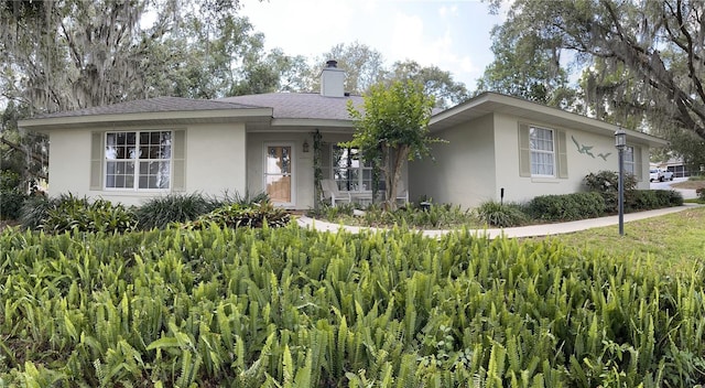 ranch-style home featuring stucco siding and a chimney