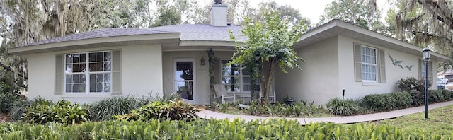 view of front facade featuring stucco siding and a chimney