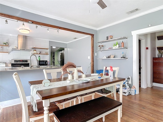 dining space featuring ceiling fan, light wood-type flooring, visible vents, and ornamental molding