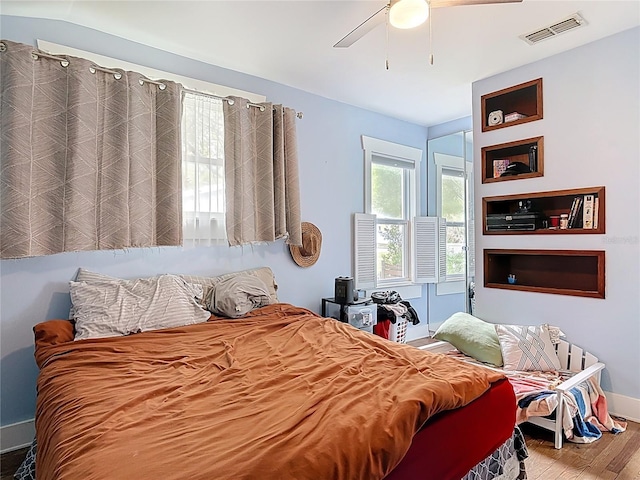 bedroom featuring multiple windows, wood finished floors, visible vents, and ceiling fan