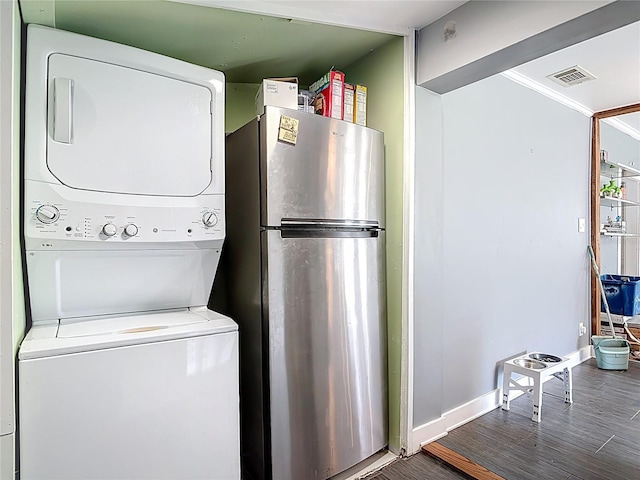 clothes washing area with baseboards, wood finished floors, laundry area, and stacked washer / dryer