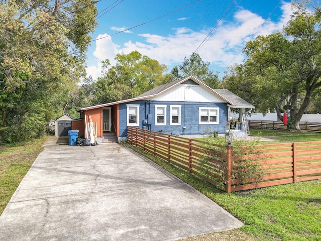 ranch-style home featuring a fenced front yard, an outbuilding, and concrete driveway