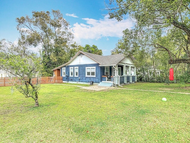 view of front facade with a front yard, a porch, fence, and roof with shingles