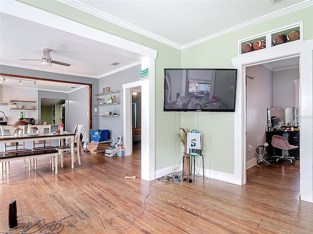 interior space with a ceiling fan, crown molding, baseboards, and wood finished floors