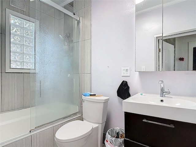 bathroom featuring vanity, toilet, and shower / bath combination with glass door