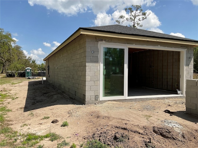 view of side of property with a garage, concrete block siding, and an outdoor structure