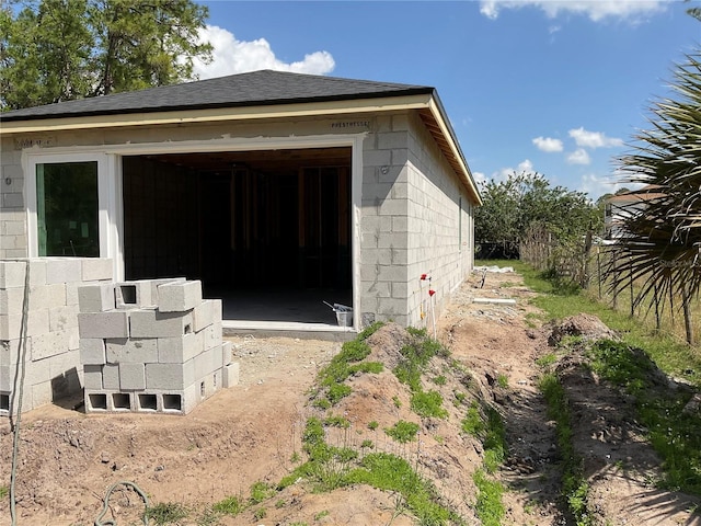 exterior space with concrete block siding and an outdoor structure