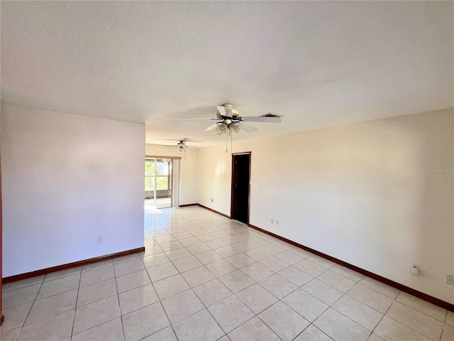 empty room with light tile patterned floors, baseboards, a textured ceiling, and a ceiling fan