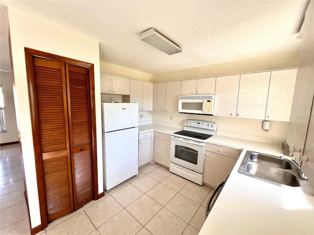 kitchen with a sink, a textured ceiling, white appliances, light countertops, and light tile patterned floors