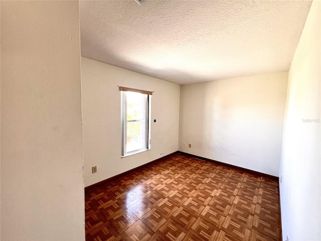 empty room with baseboards and a textured ceiling