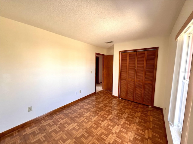 unfurnished bedroom with visible vents, baseboards, a closet, and a textured ceiling