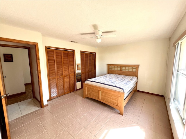 bedroom featuring visible vents, ceiling fan, baseboards, and multiple closets