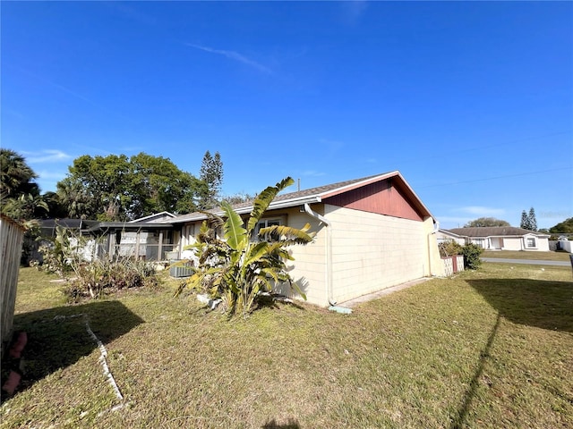 view of home's exterior featuring a lanai and a lawn