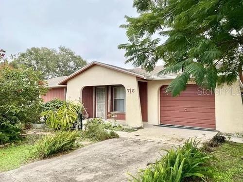 single story home with an attached garage, stucco siding, and concrete driveway