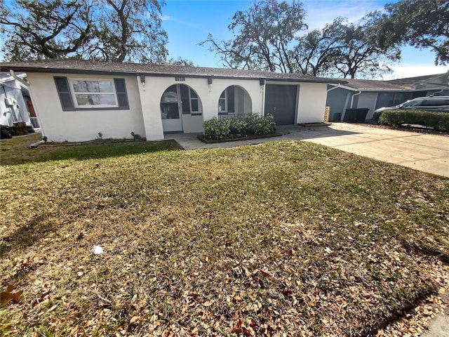 ranch-style home featuring stucco siding, a garage, concrete driveway, and a front yard