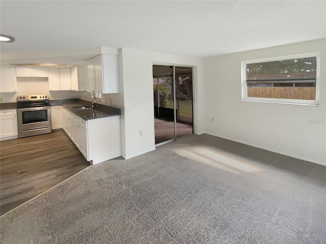 kitchen with a sink, electric range, dark countertops, and white cabinetry