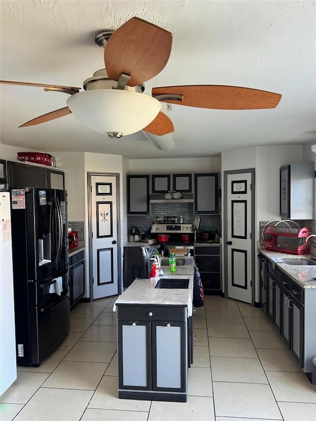 kitchen with a center island with sink, black fridge, a sink, stainless steel electric stove, and light tile patterned flooring