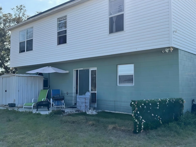 rear view of house with an outbuilding, a storage unit, and a patio