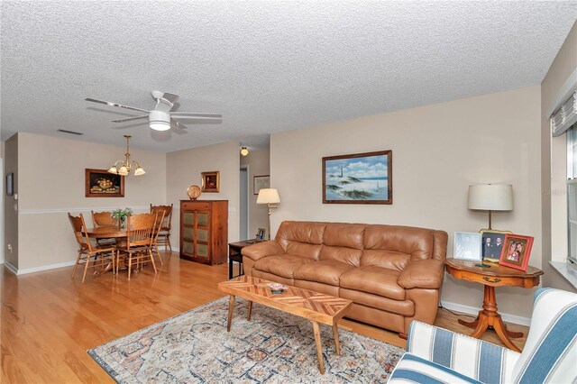 8787 SW 90th Ln Unit E, Ocala, FL 34481 - living area with a textured ceiling, wood finished floors, ceiling fan with notable chandelier, and baseboards