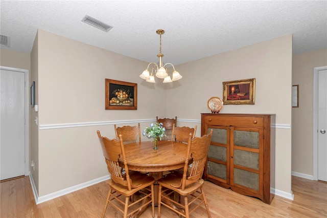8787 SW 90th Ln Unit E, Ocala, FL 34481 - dining area with visible vents, light wood-type flooring, an inviting chandelier, and a textured ceiling