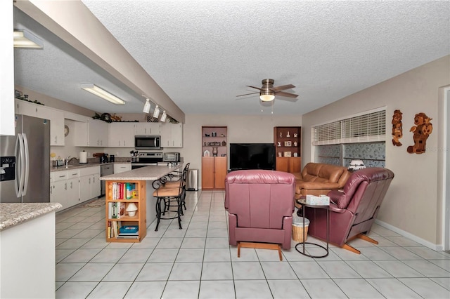 8787 SW 90th Ln Unit E, Ocala, FL 34481 - living area featuring light tile patterned flooring, a textured ceiling, ceiling fan, and baseboards