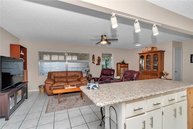 8787 SW 90th Ln Unit E, Ocala, FL 34481 - kitchen featuring light tile patterned floors, open floor plan, a ceiling fan, a textured ceiling, and white cabinetry