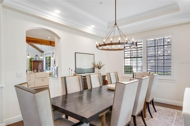 dining area with arched walkways, an inviting chandelier, a raised ceiling, and baseboards