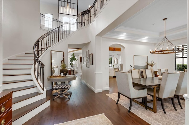 dining space featuring baseboards, arched walkways, hardwood / wood-style flooring, crown molding, and a notable chandelier