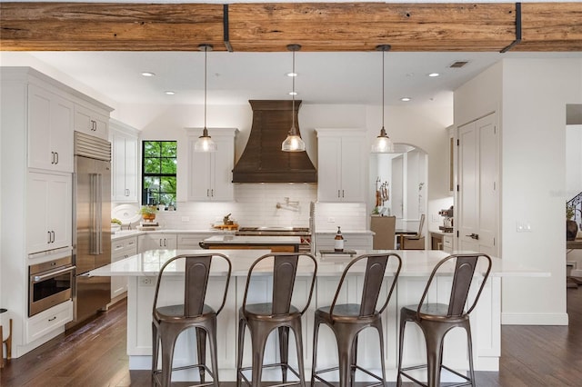 kitchen with premium range hood, tasteful backsplash, appliances with stainless steel finishes, and dark wood-style floors